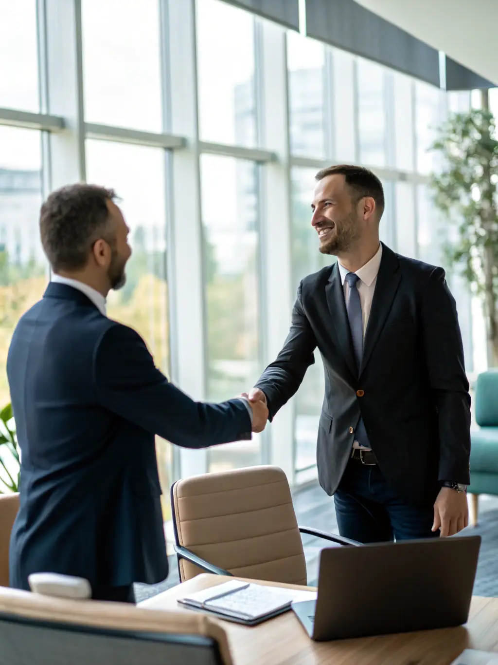 A consultant in a suit shaking hands with a client over a table with documents, symbolizing a successful consulting engagement.